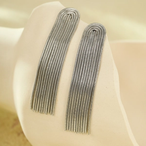 Macro shot of silver tiered snake chain tassel earrings on a minimalist display stand
