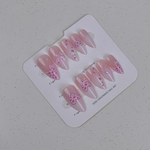 Vue détaillée des ongles amandes roses avec nœuds, motif léopard et perles de nacre