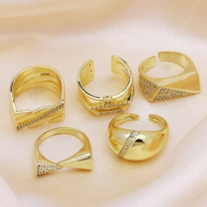Set of five gold plated copper rings with cubic zirconia on pink silk fabric