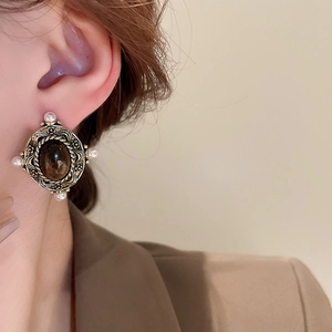 Detail of vintage bronze stud earring with oval tiger eye stone and four pearl accents