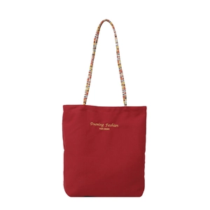 Bolso tote de lona rojo oscuro con asas trenzadas coloridas y costuras en contraste