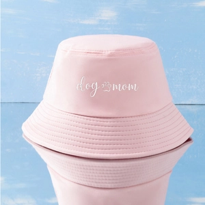 Detailed close-up of a pink Dog Mom bucket hat with mirror reflection on blue background