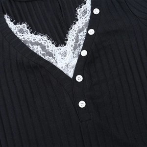 Dettaglio dello scollo a V con pizzo bianco e bottoni su un abito in maglia a coste nere