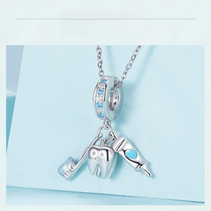 Detail of S925 silver charm with toothbrush, smiling tooth, and toothpaste tube pendants