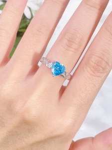 Macro detail of heart-shaped blue gemstone ring with intricate silver band carvings