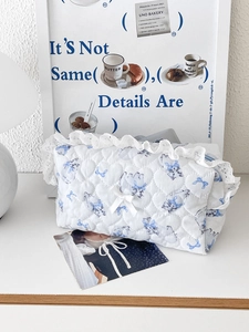 Detailed close-up of blue cat print quilted cosmetic bag with white lace trim and bow