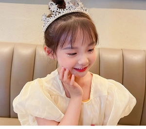 Toddler girl wearing a silver crystal princess crown tiara for birthday or performance
