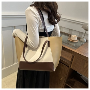 Detail of a tri-color minimalist tote bag in beige and brown shown on a model