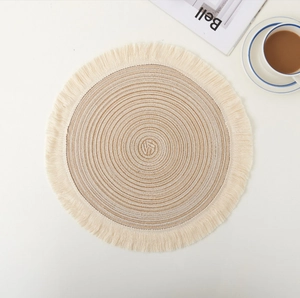 Macro view of woven round placemat showing beige spiral texture and tassel edges