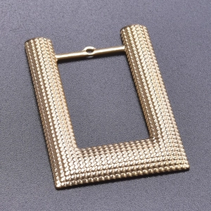 Close-up of golden rectangular stainless steel connector with grainy texture and top ring