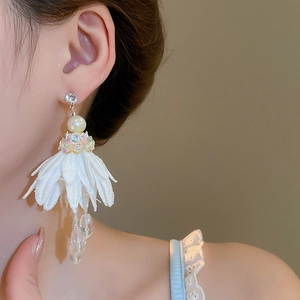 Detailed view of layered white fabric flower earrings with crystal tassels and pearls