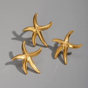 Three gold starfish earrings and ring set with polished metal finish on grey background
