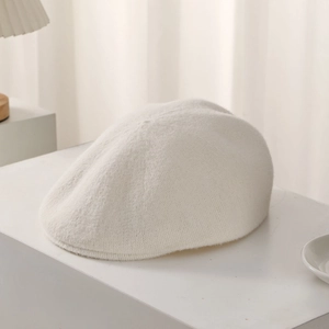Detailed macro view of cream-white knitted beret with soft cashmere-like texture details