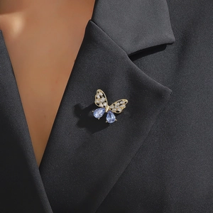 Golden butterfly brooch with zircon crystals and blue gemstones on black suit lapel