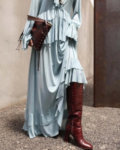 Detail of bohemian light blue ruffled maxi skirt paired with red crocodile texture boots
