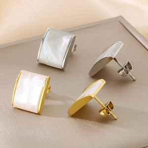 Macro shot of square stainless steel stud earrings in gold and silver with shell inlay