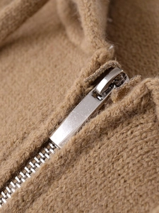 Detail of high-quality silver metal zipper on soft brown knitted drawstring hoodie jacket