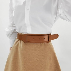 Close-up of a wide brown leather belt with metal rivets on a white shirt and skirt