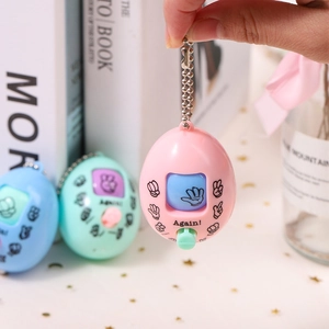 Mini rock paper scissors egg game keychain in pink blue and mint colors on a desk