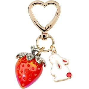 Detail of a golden heart-shaped clasp with 3D red strawberry and white bunny charms