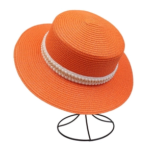 Detail of orange straw hat featuring white pearl trim and golden chain decoration