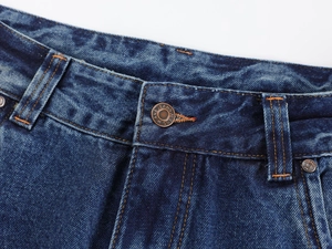 Detailed close-up of dark blue washed denim jeans waist with a branded metal button