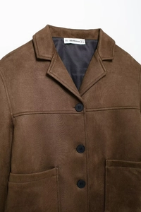 Close-up of brown faux suede jacket collar with black buttons and detailed brand tag