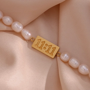 11:11 Engraved gold pendant and white freshwater pearl bracelet on champagne satin fabric