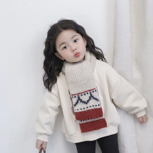 Close-up of kids knitted scarf with red color block and geometric wave patterns