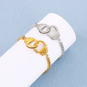 Close-up of gold and silver handcuffs bracelets displayed on a white stand