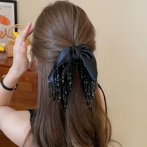 Pince à cheveux élégante avec nœud noir et pompons portée par un mannequin