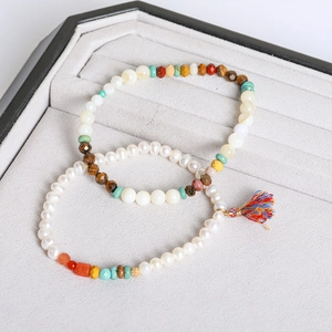 Detailed view of handmade pearl and colorful gemstone bracelets on a velvet display tray