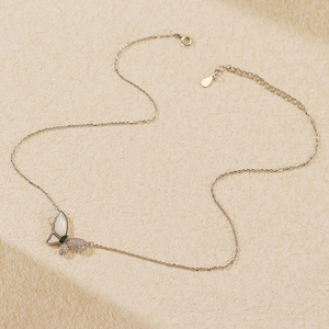 Detailed view of silver butterfly pendant with white shell wings and green gemstone