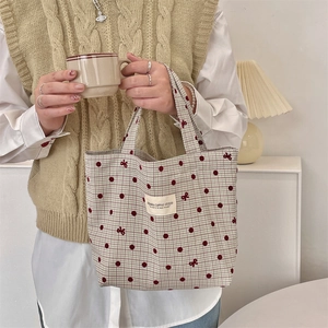 Détail du sac à lunch en toile à pois rouges et broderie de nœud dans un cadre lifestyle