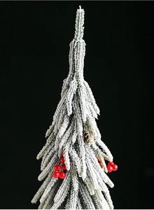 Detail of flocked artificial Christmas tree with red berries and natural pine cones