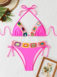 Detail of rose pink bikini featuring colorful crochet floral edges on a white background