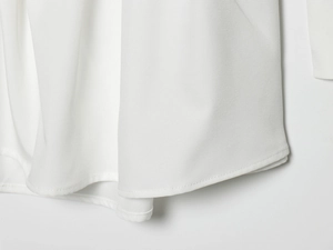 Detailed close-up showing the double-needle stitching and fabric texture on white dress hem