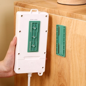 Wall-mounted power strip holder with green sliding mount on wooden cabinet surface