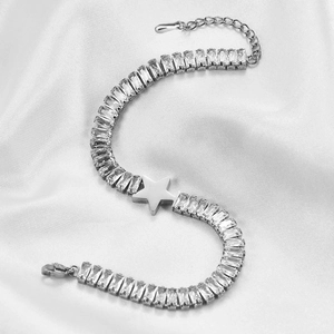 Macro detail of silver star bracelet with rectangular zircons on white silk background