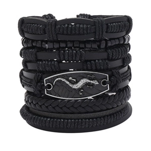 Detail of a black leather multi-layer bracelet featuring a metal plate with a lizard engraving