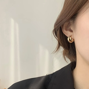 Detailed close-up of a model wearing gold triple-layered spiral hoop earrings