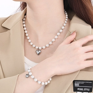 Close-up of elegant pearl and silver bead jewelry set with heart pendants on a model