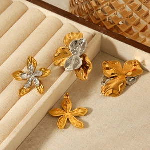 Detail view of two-tone and gold flower earrings on a beige velvet jewelry tray