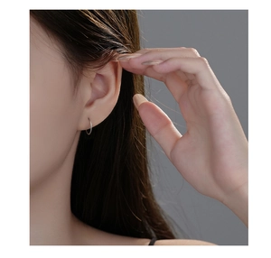 Close-up of minimalist S999 sterling silver hoop earrings worn on female ear lobe