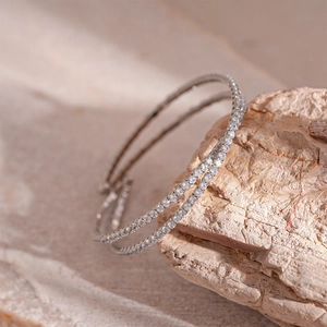 Bracelet tennis à double rangée en zircons argentés exposé sur une pierre brute