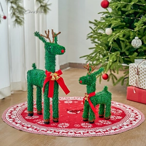 Pair of green reindeer Christmas decorations with red bows and gold bells on a snowy mat