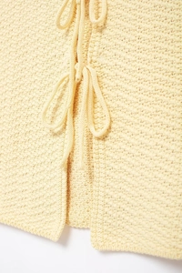 Detailed macro shot of light yellow waffle knit vest with double tie-front bow design