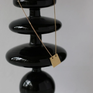 Detail of square matte brushed 18K gold plated pendant on a fine titanium chain
