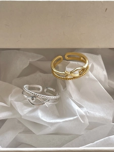 Macro detail of silver and gold fish-shaped layered rings with zircon on white art paper