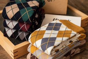 Flat lay of colorful argyle pattern knee-high socks in a cozy wooden tray
